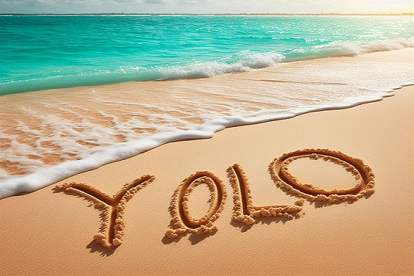 le mot yolo ecrit sur le sable sur une plage paradisiaque