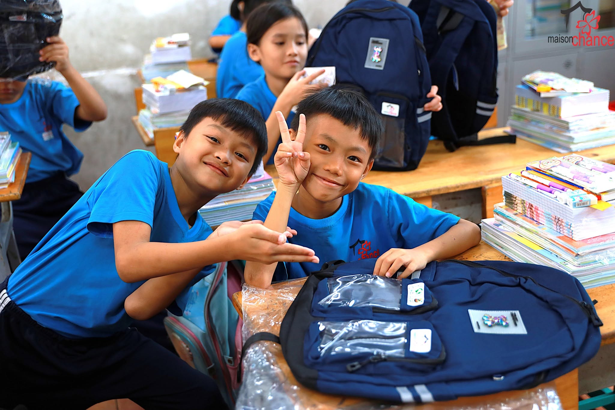 Deux élèves de l'école du Village Chance posent fièrement à côté de leur nouveau cartable